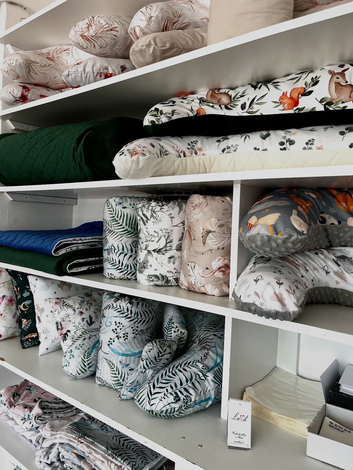 Shelves filled with finished LaLove.it pregnancy and nursing pillows in the workshop